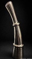 full view of chrome sculptural vase against dark background
