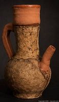 Front view showing speckled body, terracotta neck, handle, and side spout