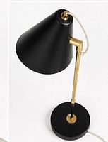Angled top view of matte black cone shade, brass arm, circular base