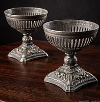 Pair of silver-tone pedestal compotes on wood surface