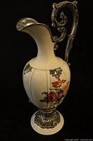 Full left profile of porcelain ewer showing floral design and silver overlay handle and base