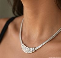 Necklace worn on model showing engraved crescent and collar texture