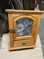 Front view of wooden jewelry cabinet with contents visible in bag