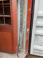 Three fishing rods leaning against cabinet and container wall