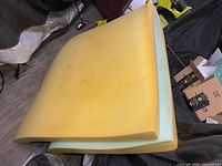 Folded yellow and blue foam mattress pad on floor