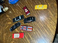 Seven die-cast cars laid out on wood surface