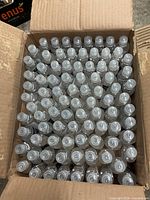 Open cardboard case filled with many identical small sanitizer bottles