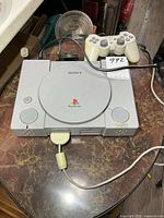 Top view of Sony PlayStation console with controller on marble surface