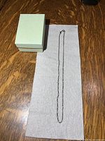 Full view of 17 inch sterling Figaro chain laid out beside box