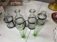 Front view of metal rack with four clear vases and two green bud vases