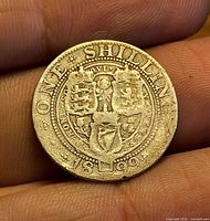 Reverse side of 1899 UK one shilling coin showing heraldic design and date