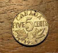 Reverse of 1924 Canada 5-cent coin on wood surface