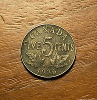 Reverse of 1936 Canada 5 cents coin showing denomination, maple leaves and date