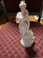 Full view of standing female figurine on patterned chair