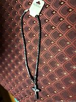 Front view of entire hematite bead necklace with cross pendant and tag