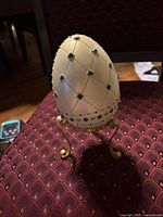 Front view of ivory decorative egg on gold-tone stand showing lattice and gemstones