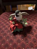 Front view of resin bird figurine on poinsettia