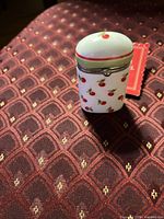 Front view of porcelain cherry trinket box on patterned surface