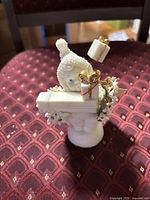Front view showing child figurine, rectangular gift, wire-mounted parcels and floral accents