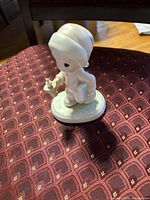 Front angled view of figurine showing candleholder and book