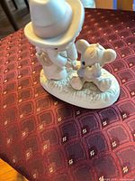 Left side view of Precious Moments child kneeling with teddy bear figurine