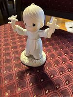 Front view of figurine showing child holding cross and lily