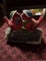 Front view of resin figurine showing birds, hats, scarves, and Welcome text