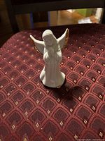 Front view of white porcelain angel figurine showing gold-trimmed wings