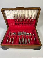 Open wooden chest showing entire flatware set arranged in slots