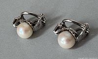 Side view of both clip-on earrings showing cultured pearls, clip mechanism, and 750 hallmark.