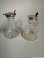 Two glass noggin decanters side by side showing overall design and sterling lids
