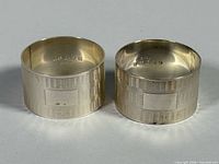 Pair of sterling silver napkin rings standing side by side showing hallmarks