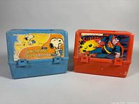 Front view of both lunch boxes, Snoopy blue and Superman orange