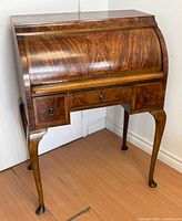 Front and right side view of burl mahogany cylinder roll-top desk showing drawers and legs