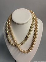 Both necklaces draped on bust form showing pearl size and color