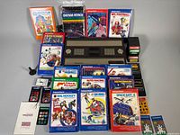 Console, boxed games, loose cartridges, overlays and accessories arranged for overview