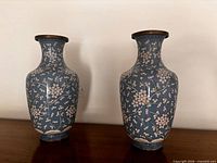 Front view of both blue painted metal vases showing pattern and shape