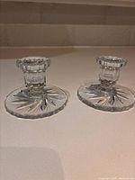 Two cut glass candlestick holders with starburst bases displayed side by side
