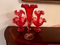 Front view showing cranberry red glass bud vase and pair of matching candlestick holders