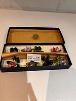 Open box showing eight floral place card holders and lid