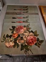 Stack of seven wooden placemats showing rose design