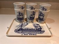 Tray with four tumblers stacked on it, showing ship graphic and text