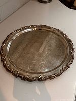 Top view of the silver-plated round tray showing ornate rim and engraved center