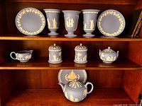 Full set of 11 Wedgwood blue jasperware pieces displayed on wooden shelves
