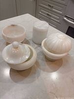 Four white stone decorative containers displayed on countertop