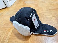 Left-side view showing FILA logo, ear flaps, sherpa lining, retail tag