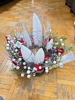 Top view of centerpiece showing glass hurricane, faux greenery, ornaments, pinecones