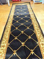 Full length view of black and gold runner rug on floor