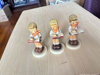 Front view of three identical Goebel Hummel Honor Student figurines