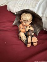 Full view of boy figurine sitting under umbrella